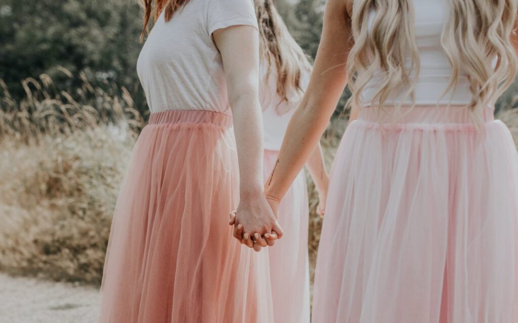 Young women hold hands in a circle, facing outward