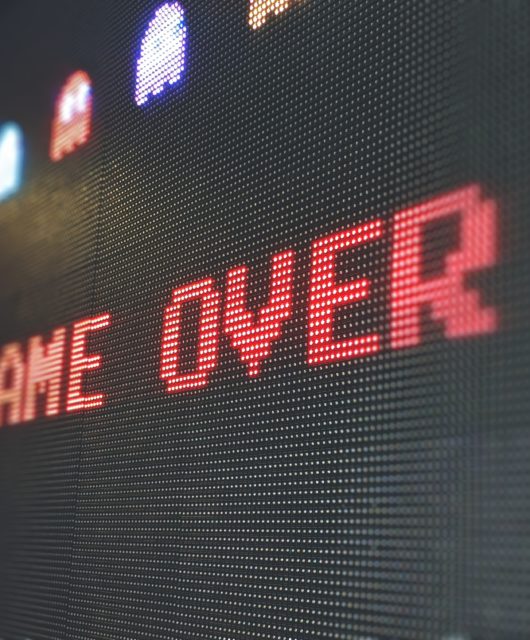 An arcade game displays the text "Game Over"