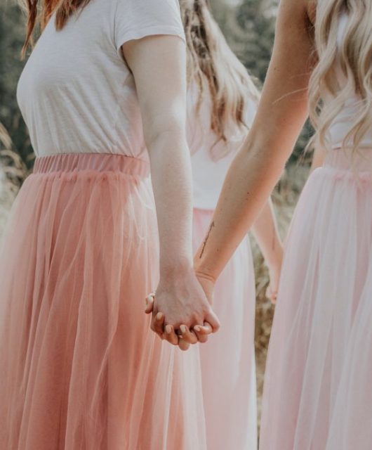 Young women hold hands in a circle, facing outward